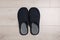 Pair of stylish slippers on white wooden floor, top view