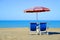 Pair of sun loungers and sunshade umbrella on the beach.