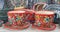 pair of teacups, red with colourful fliwer decoration with colourful ceramic dishes background, samarkand market, bazaar