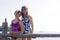 Pair of teen girls standing at wooden rail rustic fence in summer bathing suits on sunny day with copy space