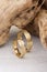 Pair of textured surface gold wedding ring bands on wooden background