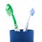 Pair of toothbrushes in blue plastic cup isolated over white background