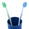 Pair of toothbrushes in blue plastic cup isolated over white background