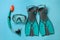 Pair of turquoise flippers and mask on light blue background, flat lay