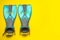 Pair of turquoise flippers on yellow background, flat lay. Space for text