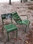 Pair of two empty garden chairs touching each other in Paris park