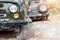 Pair of two old retro vintage 4x4 soviet suv vehicle on dirt gravel unpaved road in summer at sunset morning sun. Off