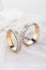 Pair of two tone gold wedding ring with matte surface and diamonds on white glossy background