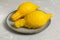 A pair of ugly lemons on a gray plate on a gray background.