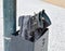 a pair of used black boots made in black leather abandoned in a black bin. Boots and bin at a post in the sidewalk of the street.