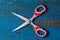 A pair of used children scissors against old blue wooden background