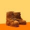 A pair of very old winter brown leather boots with wooden sole. Minimalist arrangement against light and dark orange