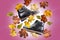 A pair of warm autumn black leather women`s boots on violet background with bunch of autumn leaves