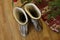 A pair of warm boots close-up in wool stands near the Christmas tree with presents at home on a wooden floor. next to a candleligh