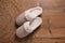 Pair of warm stylish slippers and wicker mat on wooden floor, flat lay