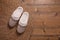 Pair of warm stylish slippers and wicker mat on wooden floor, flat lay. Space for text