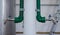 Pair of water taps in green plastic pipes on light background