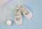Pair of white baby booties on blue background with lace christen