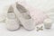 Pair of white baby shoes on embroidered christening white dress, cross and candle