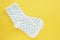 a pair of white in black speckled cotton socks on a bright yellow background.