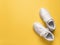 Pair of white chunky sole sneakers over an yellow amber paper background. New unisex tied laces shoes for active lifestyle,