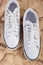 Pair of White Fashionable Laced Trainers On Wooden Surface.