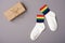 Pair of white socks with rainbow edging and gift box on gray background, idea for gift lgbt friends