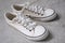 A pair of white unisex sneaker shoes laid out on a cement floor