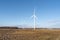 A pair of wind turbines turn in an empty field