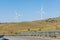 A pair of windmills on a clear blue sky in the Sierra del Merengue next to a meadow with cows in Plasencia.