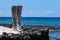 Pair of wooden status Tikis, place of refuge Honaunau, Hawaii. White sand, wall of black lava rock, ocean and blue sky.