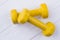 Pair of yellow dumbells on white wood background.