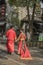 A pair of young couples who are facing each other wearing Chinese traditional red wedding dresses and smiling at each other in the