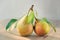 Paired fruit - two pears on one stalk with leaves. With drops of water, lit by the sun on a wooden background.