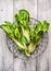 Pak choi in metallic basket on white wooden background