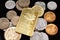 Pakistani coins with a gold Canadian ingot on a black reflective background