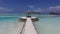 Palapa and sunbeds on maldives beach pier over sea