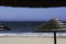 Palapas On The Beach With Sailing Boat At Anchor