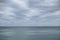 Pale cloudy sky over dim greyish sea water