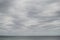 Pale cloudy sky over dim greyish sea water