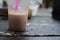 A pale coffee in side a plastic glass on a wood table.