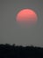 Pale orange sun with smoke layered clouds over FingerLakes sky