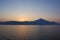 Pale orange sunset behind island mountain silhouette