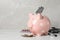 Pale pink ceramic piggy bank with money, stethoscope and pills on white table, space for text. Medical insurance