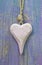 Pale pink rustic wooden heart on purple wooden surface for greet