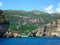 Paleokastritsa in Corfu Island, Greece, beach and rocky cliffs covered in green vegetation.