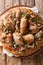 Palestinian dish of chicken with sumac, pine nuts and onions on a flat bread closeup. Vertical top view