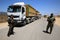 Palestinian security officers stand next to Palestinian trucks at a checkpoint before heading to the Israeli side at the Kerem Sha