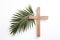 Palm Sunday. Wooden cross and palm leaf on white background with copy space.