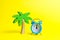 Palm tree and blue alarm clock on a yellow background. Time for rest and relaxation. Travel, vacation, cruise. Tourism